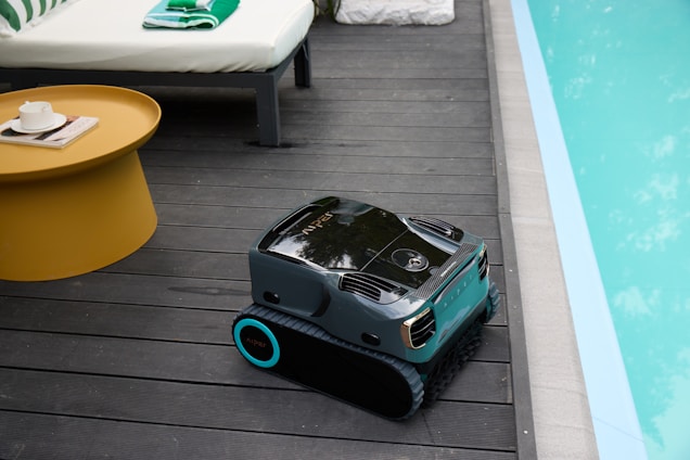 Robotic pool cleaner on wooden deck by pool