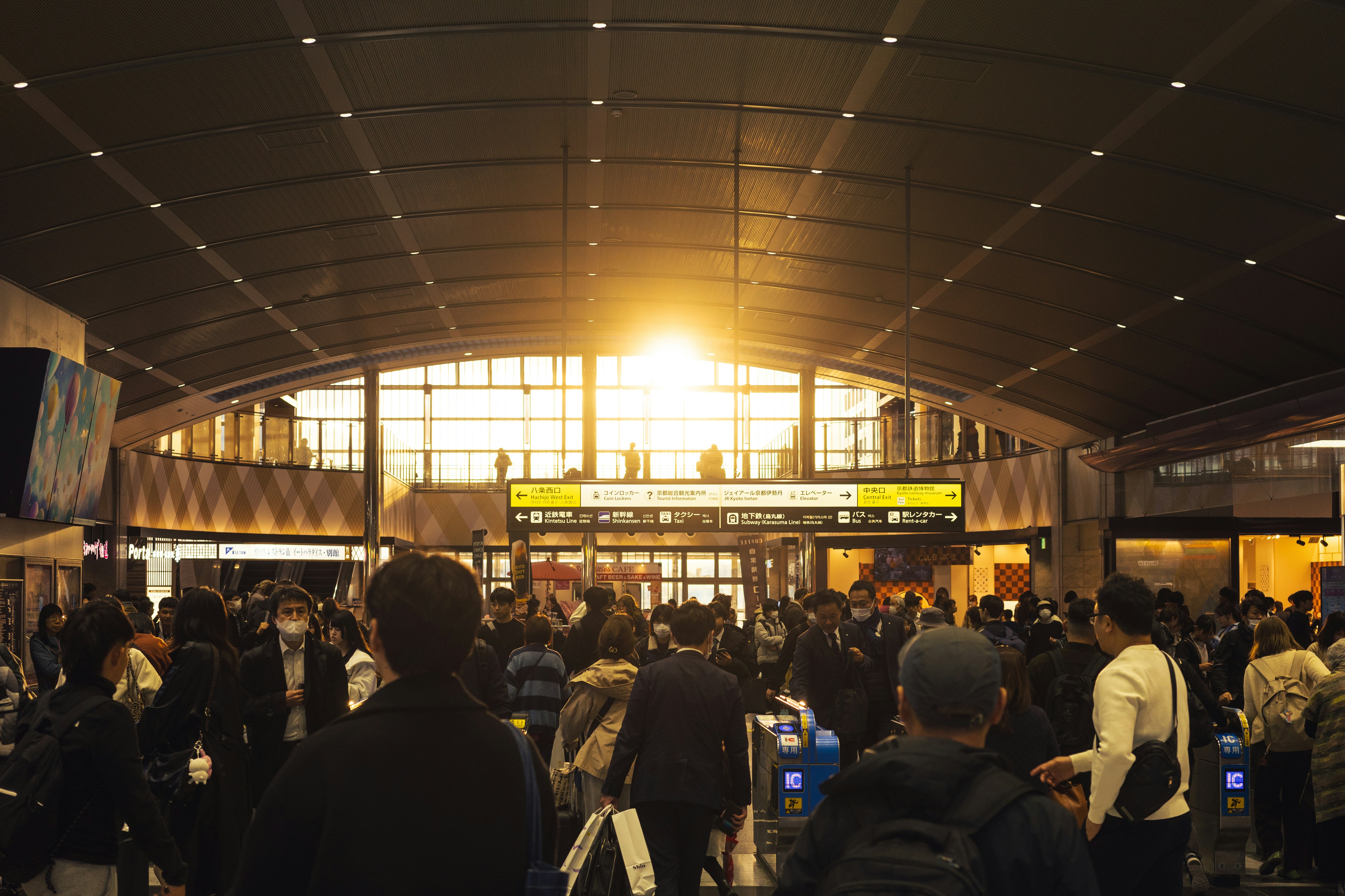 Crowd of people in a busy train station at sunset.