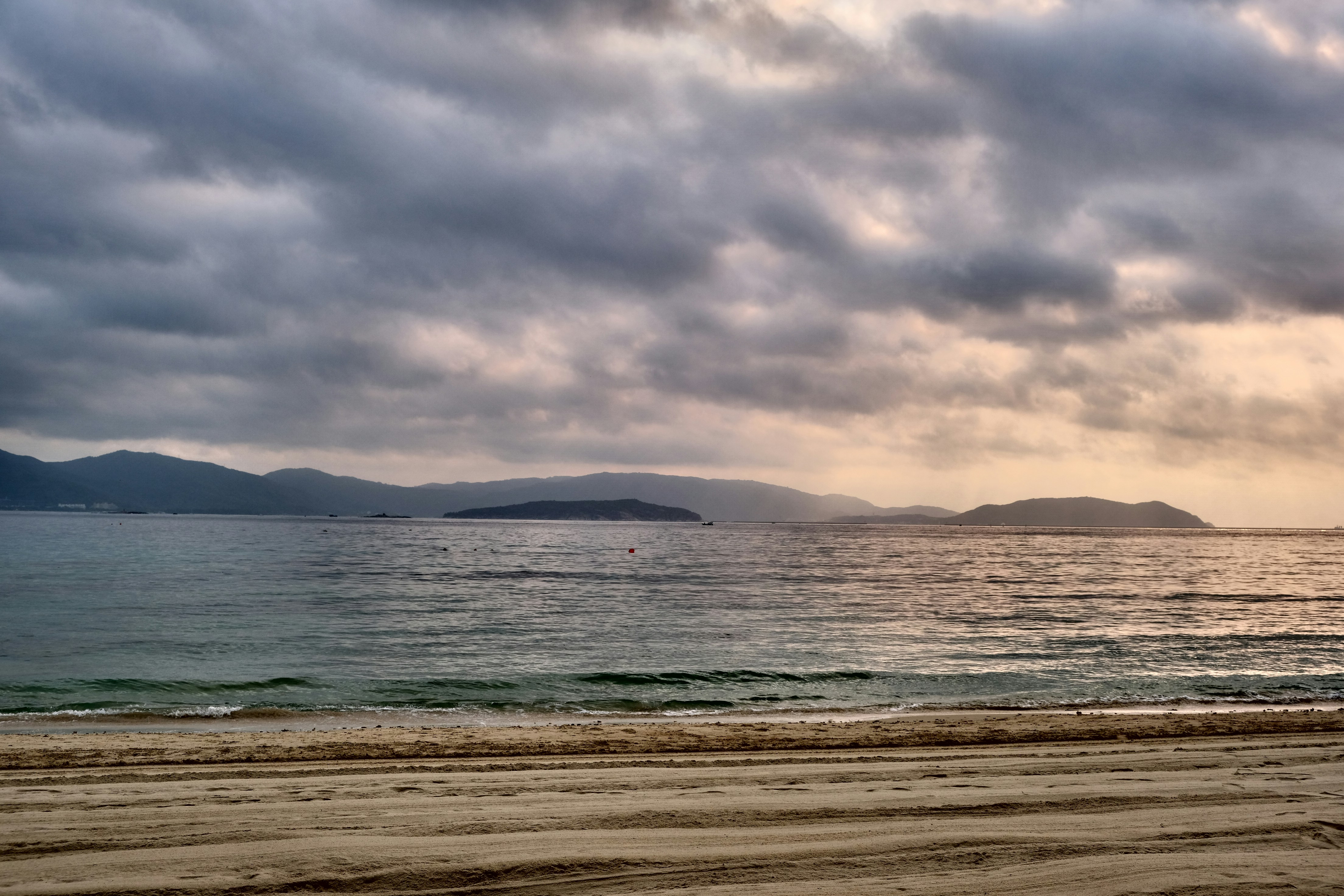 Beach with calm ocean under cloudy sky