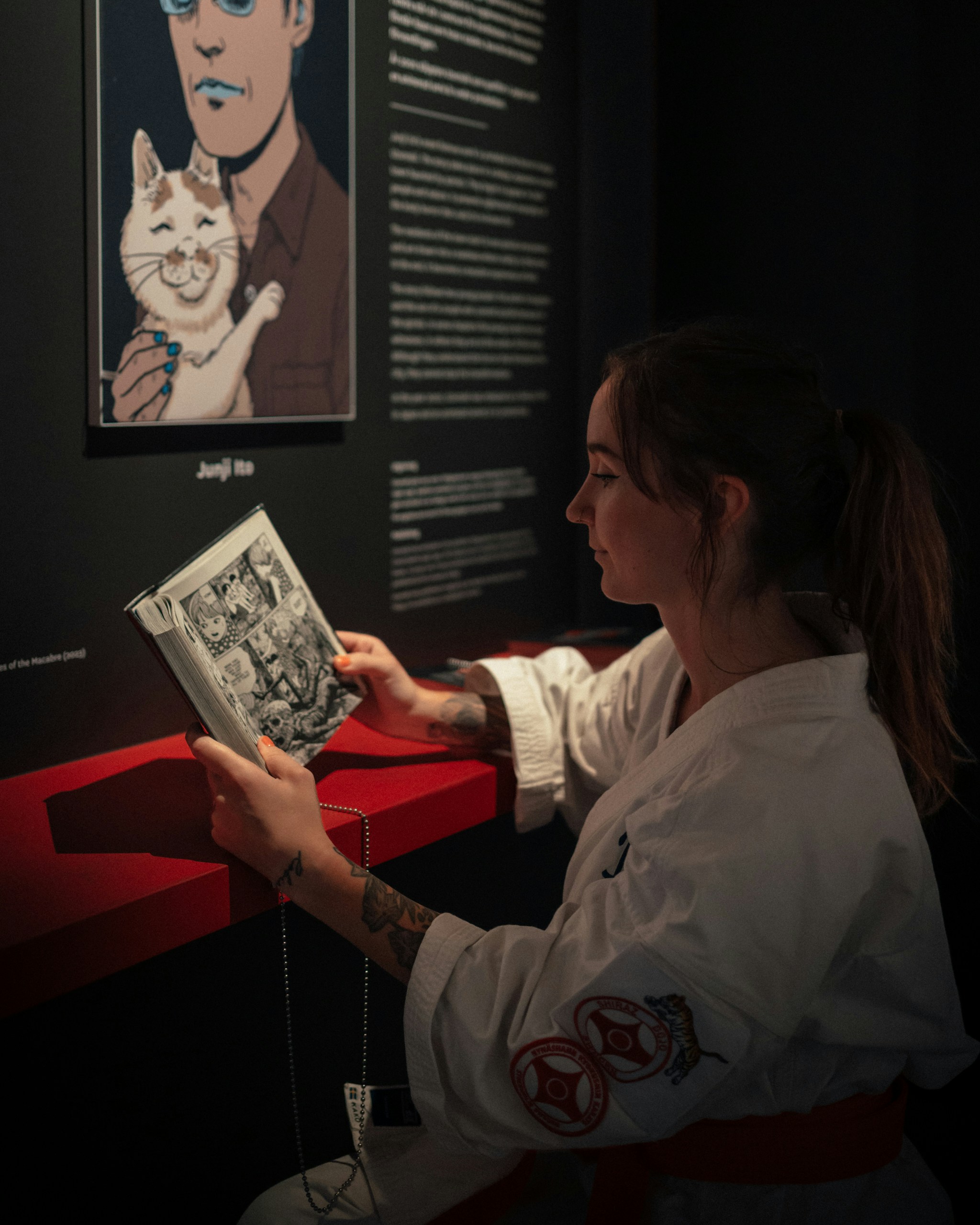 Woman in martial arts uniform reads a book.