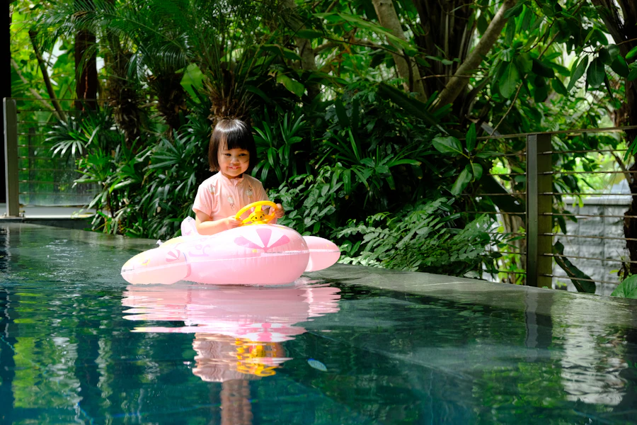 A toddler drifting on a float in the warm pool, surrounded by greenery