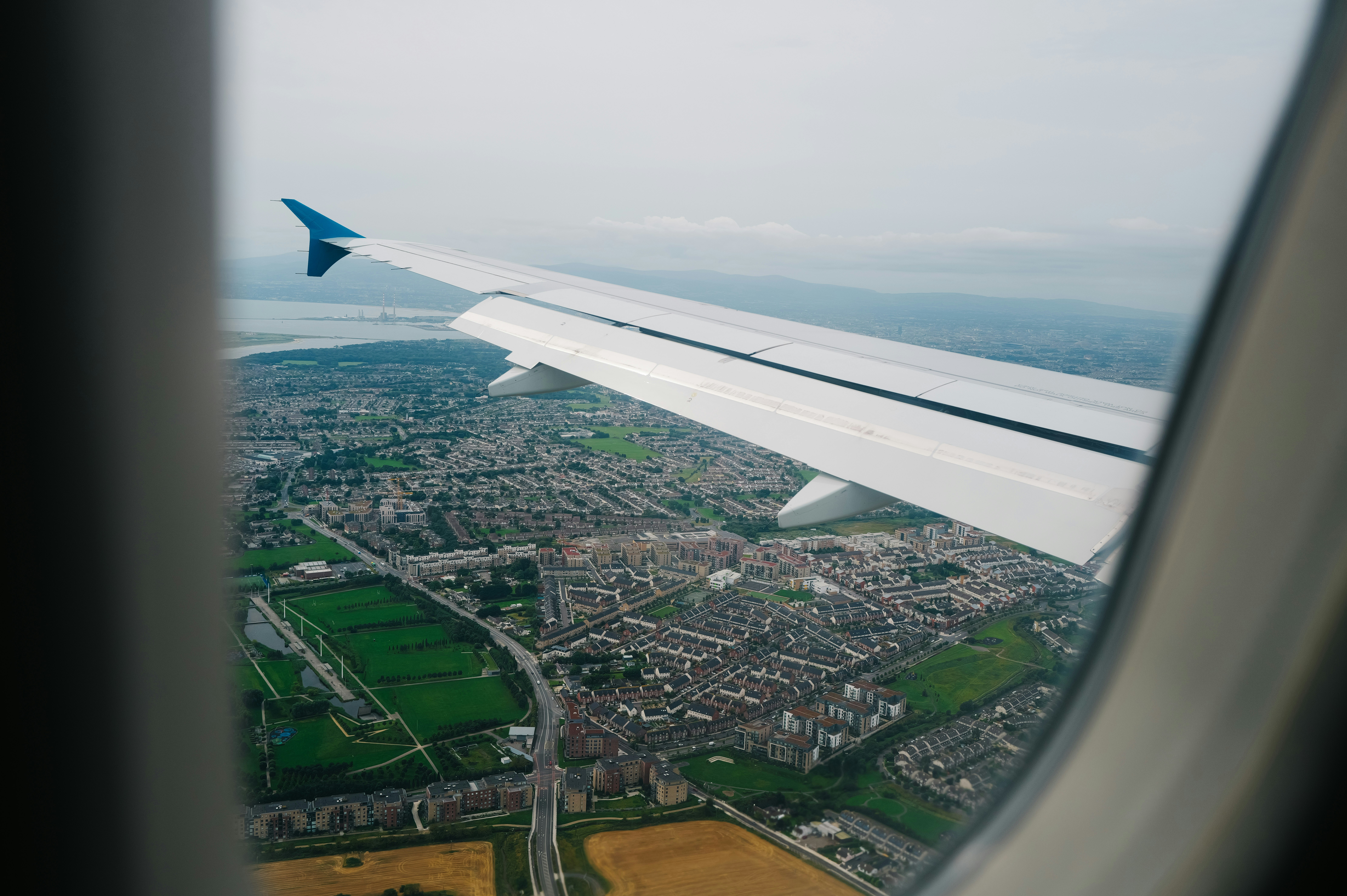 Airplane wing over a sprawling city landscape.