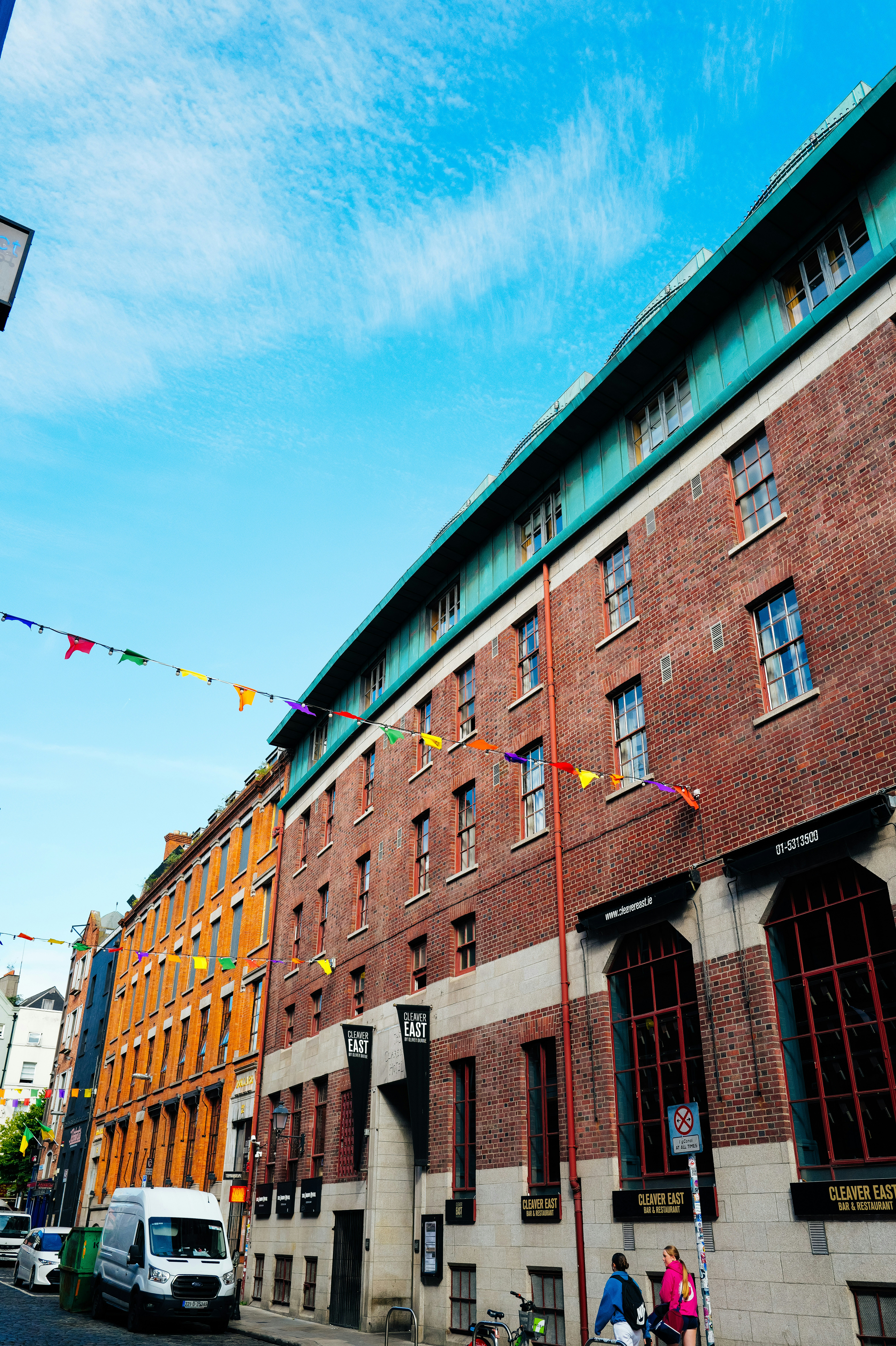 Brick buildings with colorful flags under a blue sky.