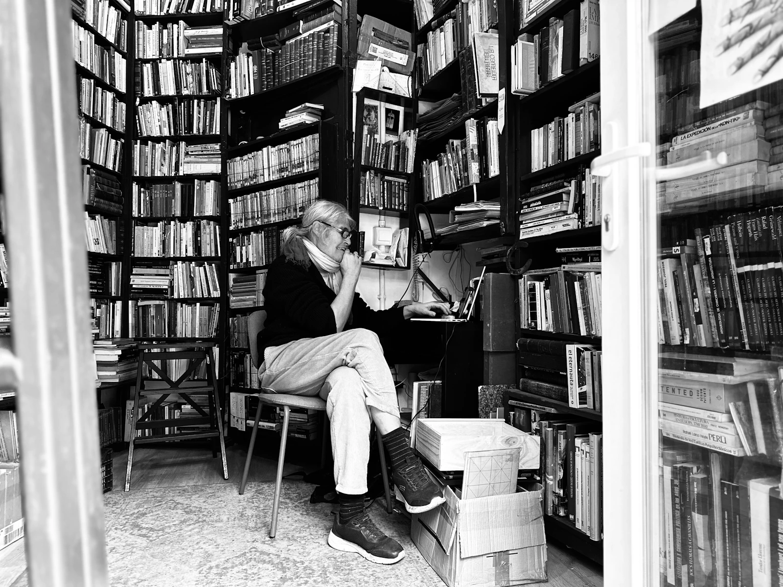 Persona sentada entre estanterías de libros, consultando normativa para preparar el temario del TAI