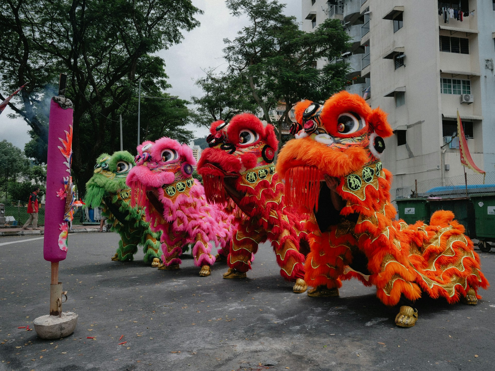 Four colorful lion dance costumes stand on a street.
