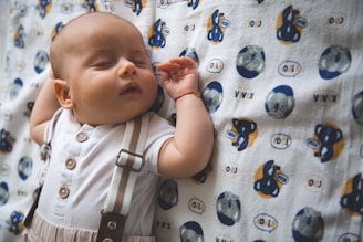 A baby sleeps peacefully on a patterned blanket.