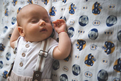 A baby sleeps peacefully on a patterned blanket.