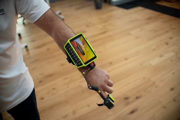 Operador con lector de escaneo montado en el brazo, escenario del marketing digital para proveedores de sistemas WMS