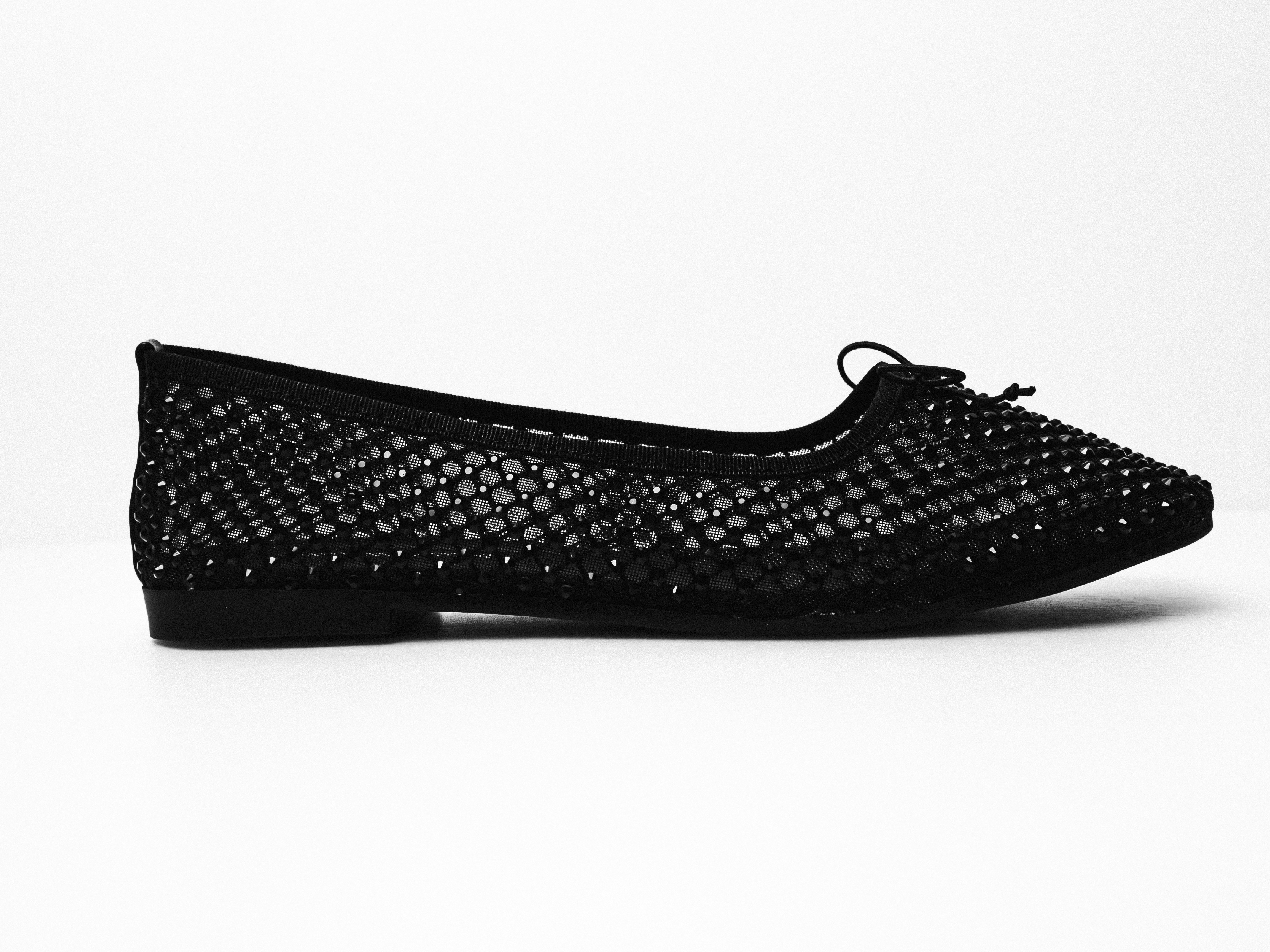 A black woven flat shoe with a bow
