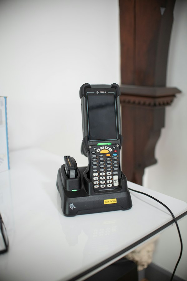 Terminal lectora de código de barras en su base de carga, hardware que acompaña al marketing digital para proveedores de sistemas WMS