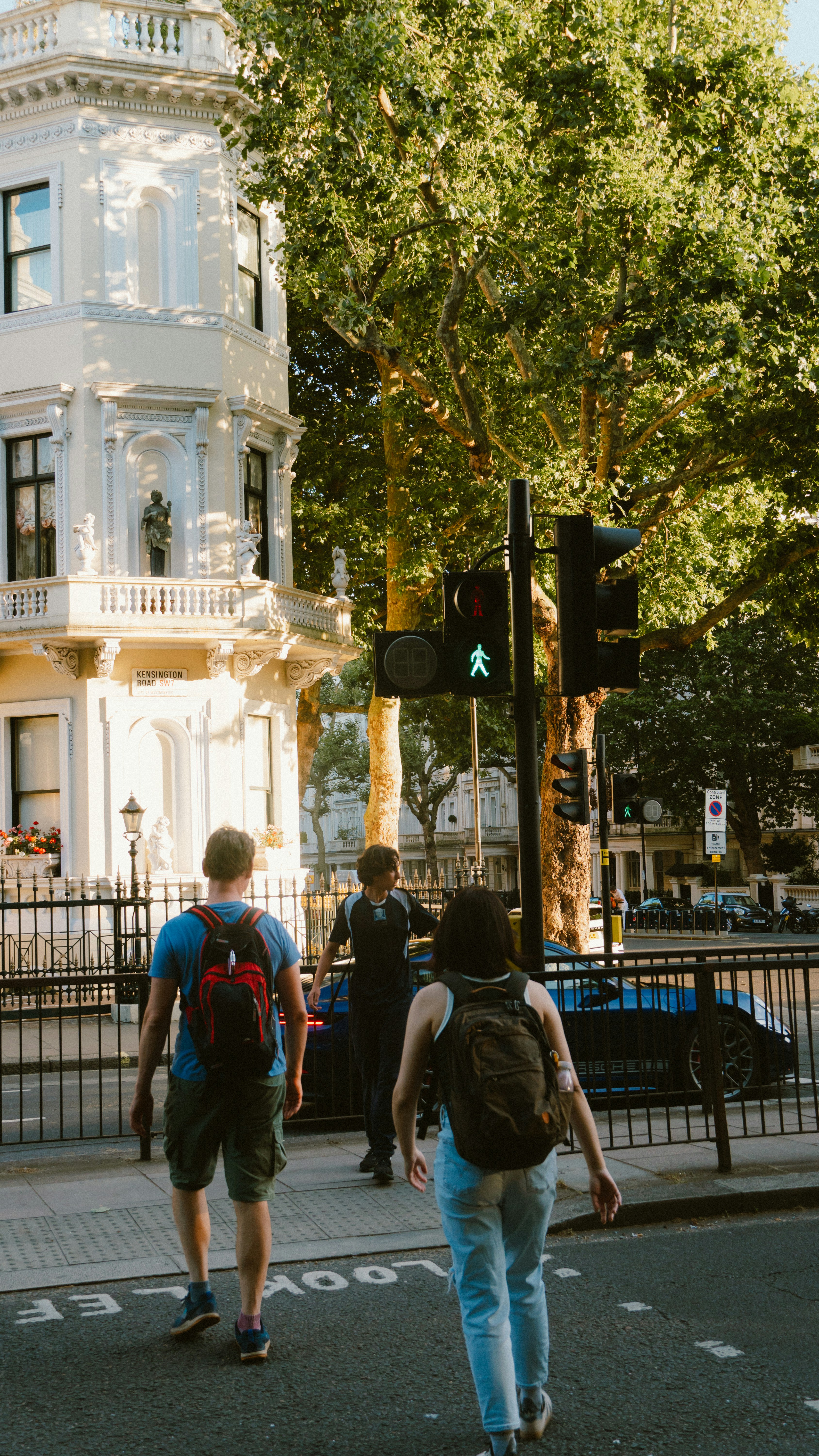 People cross street at a pedestrian crossing with traffic light.
