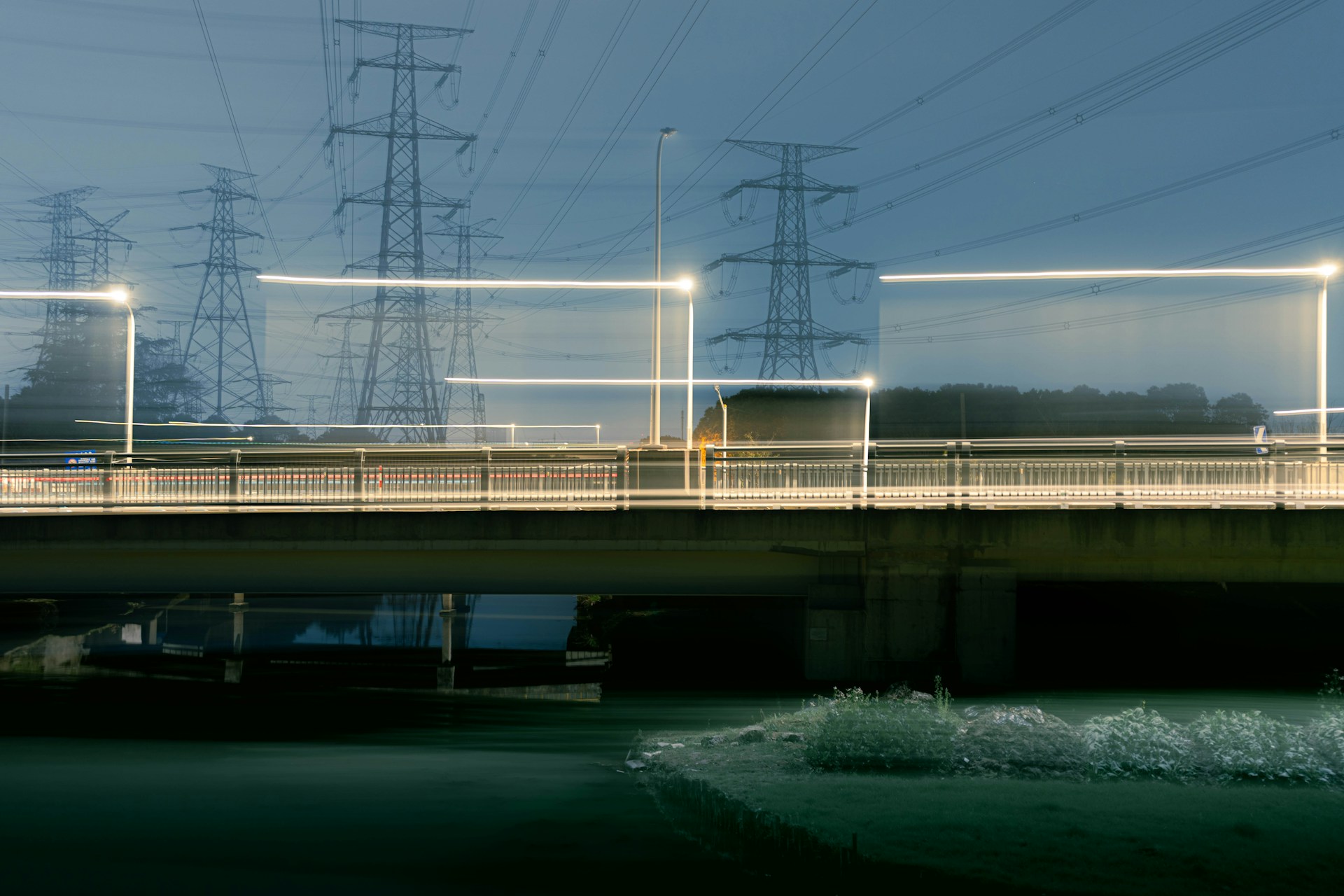 Power lines and bridge with light trails at dusk