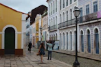 People walking on a cobblestone street lined with colorful buildings