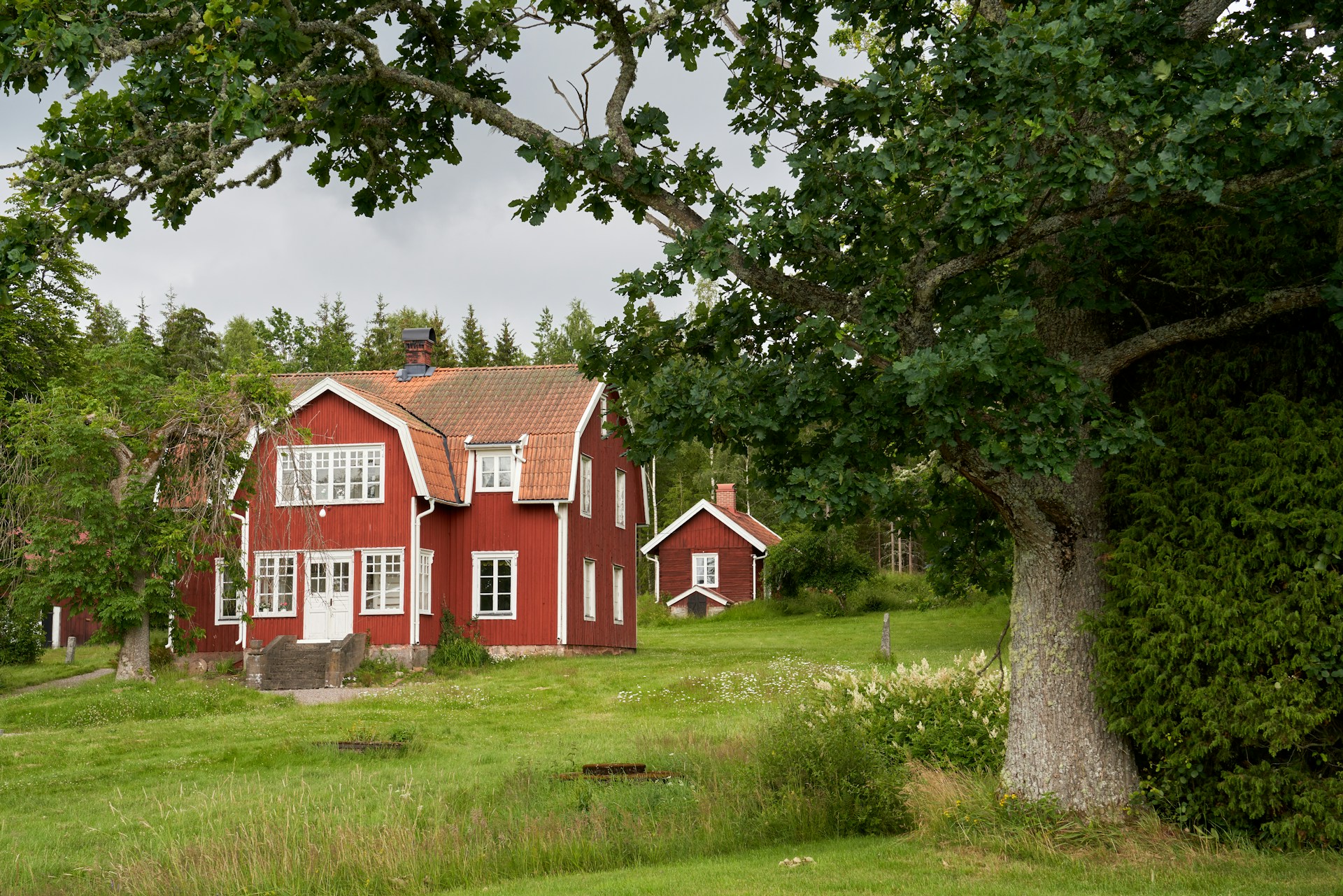 Red wooden house in a lush green landscape.