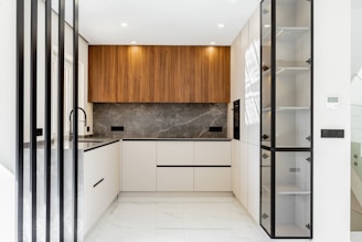 Modern white and wood kitchen with marble backsplash.