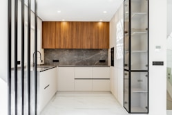 Modern white and wood kitchen with marble backsplash.