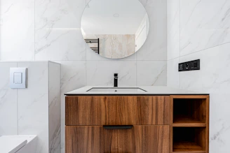 Modern bathroom vanity with marble tiles and round mirror
