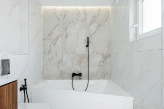 Modern bathroom with white marble and bathtub.