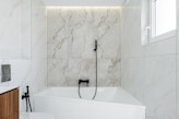 Modern bathroom with white marble and bathtub.