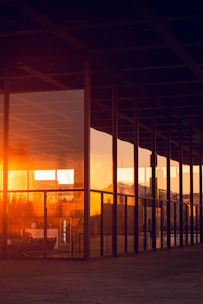 Sunset reflects on a modern building's glass facade.