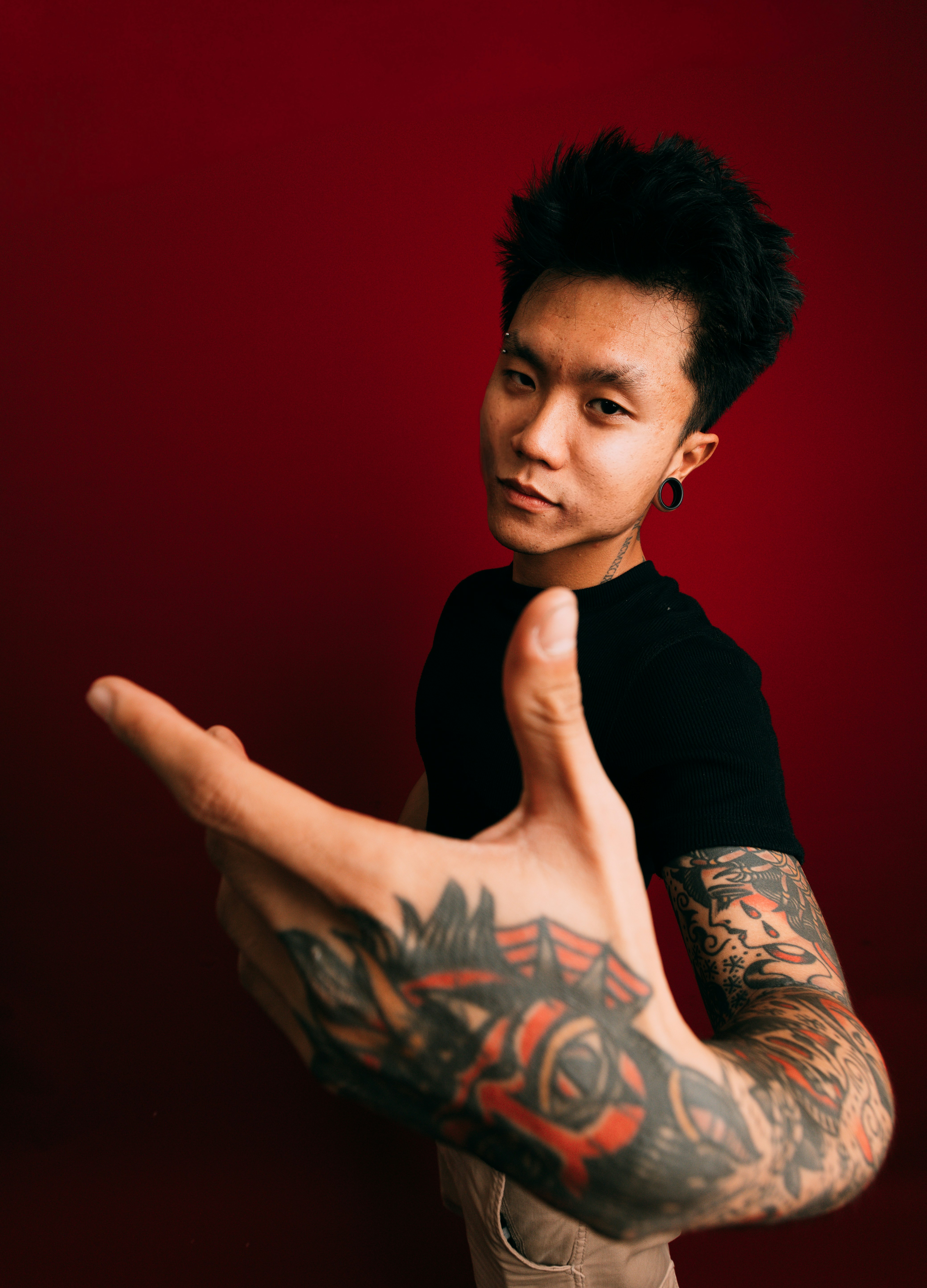 Tattooed man with hand extended on red background