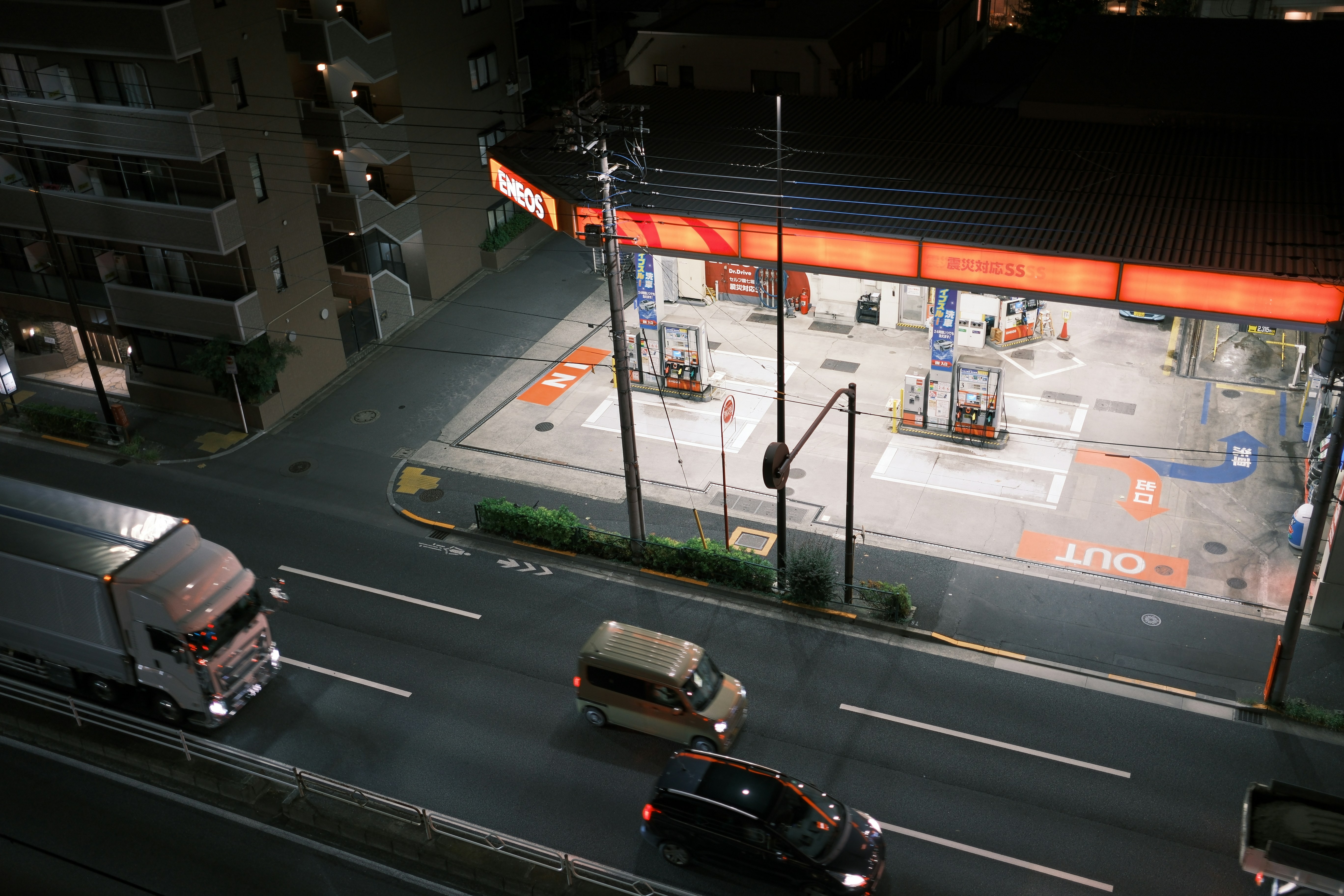 Diverse vehicles driving past a modern gas station.