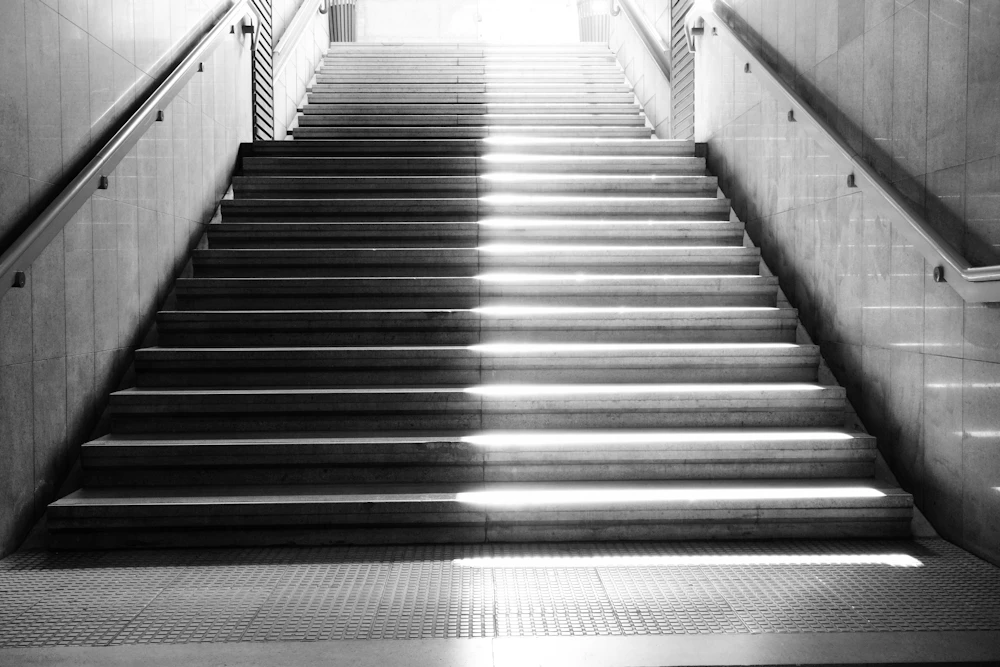 Sunlight streams down a concrete staircase, drawing hard stripes of shadow