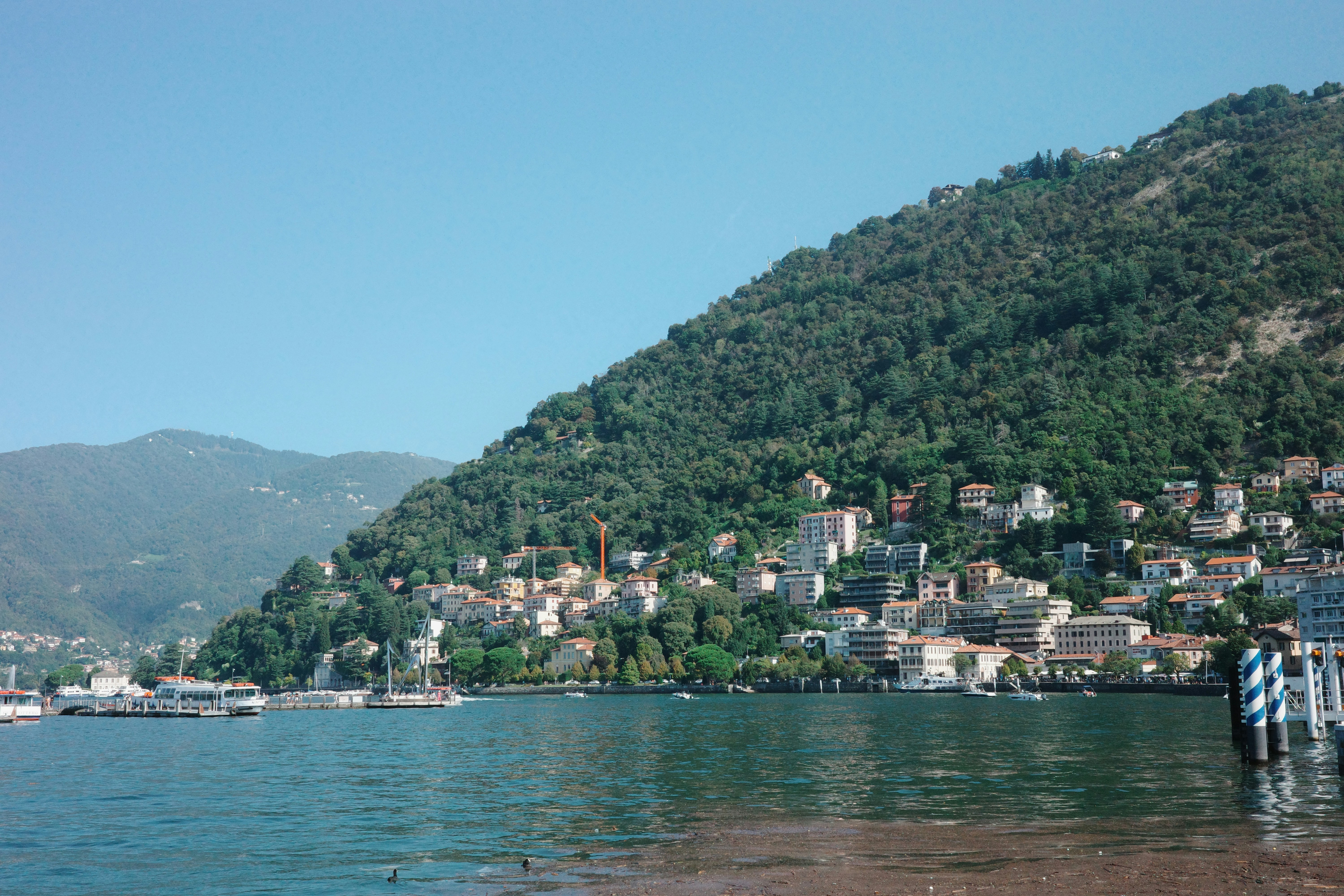 Buildings nestled on a tree-covered mountainside overlooking a lake.