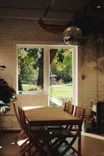 Wooden table and chairs near a window overlooking garden