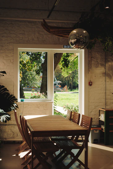 Wooden table and chairs near a window overlooking garden
