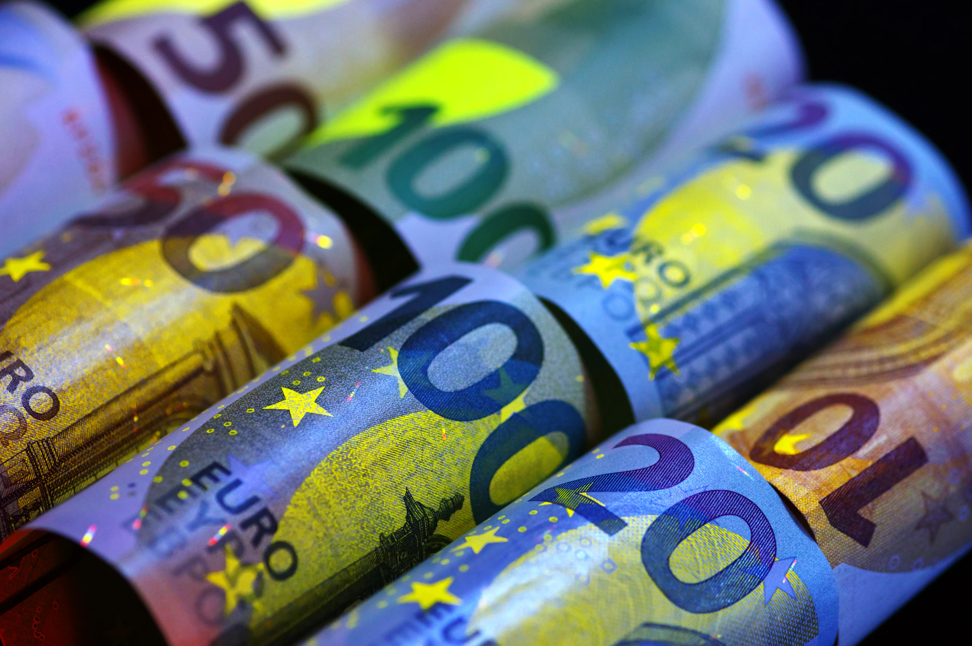 Rolled euro banknotes illuminated under uv light