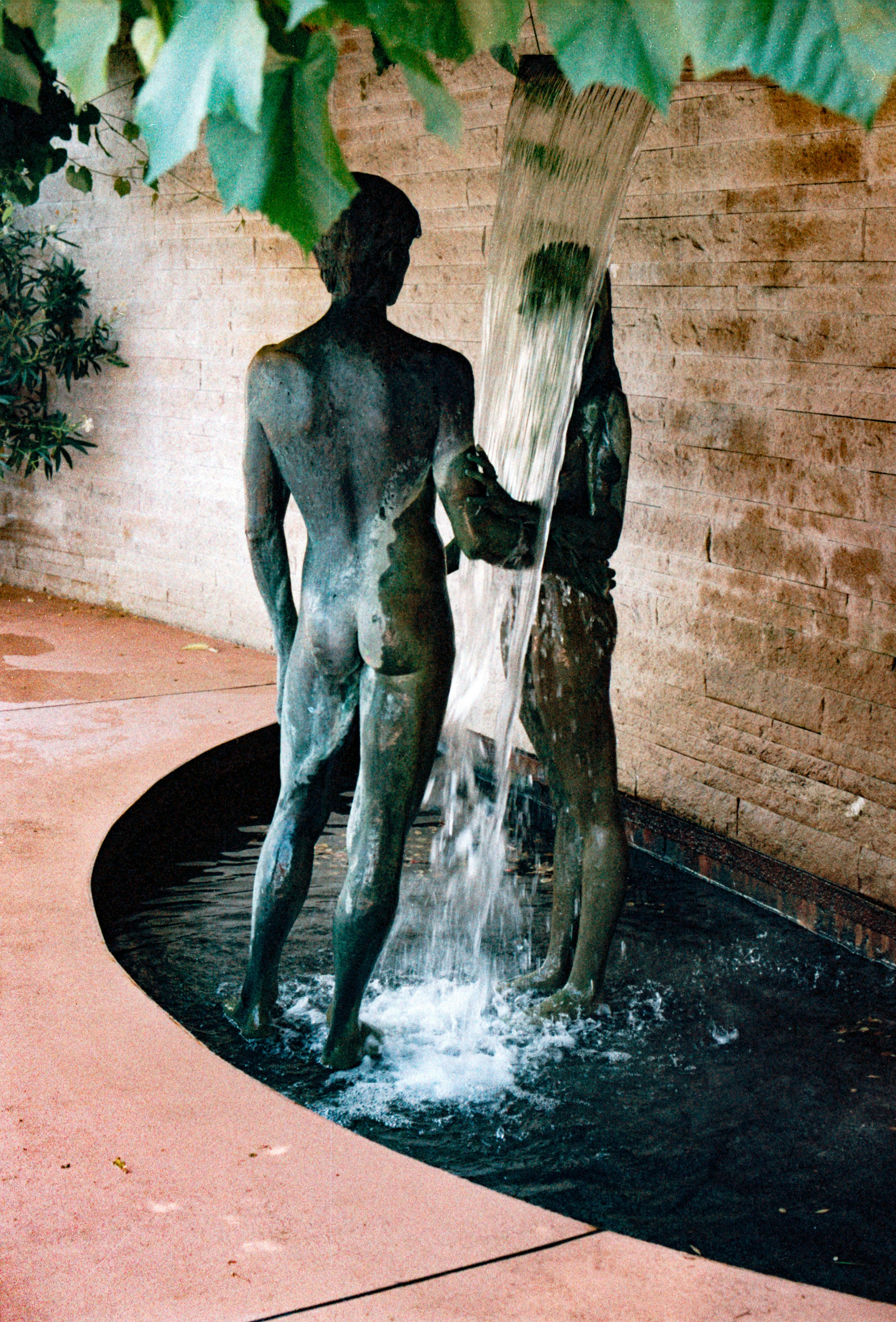 Bronze statues of two people under a waterfall.