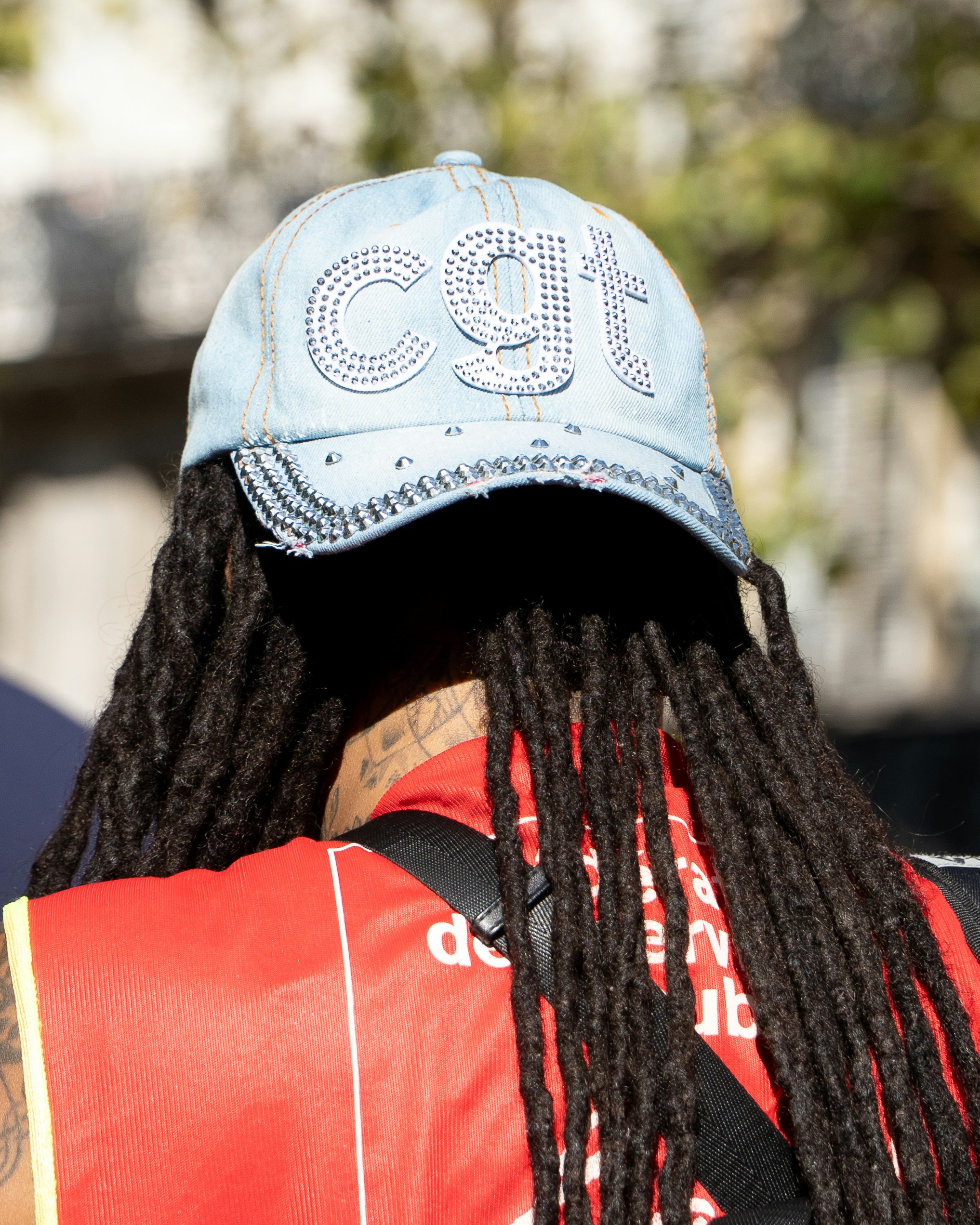 Person with dreadlocks wearing a sparkly 'cgt' baseball cap.