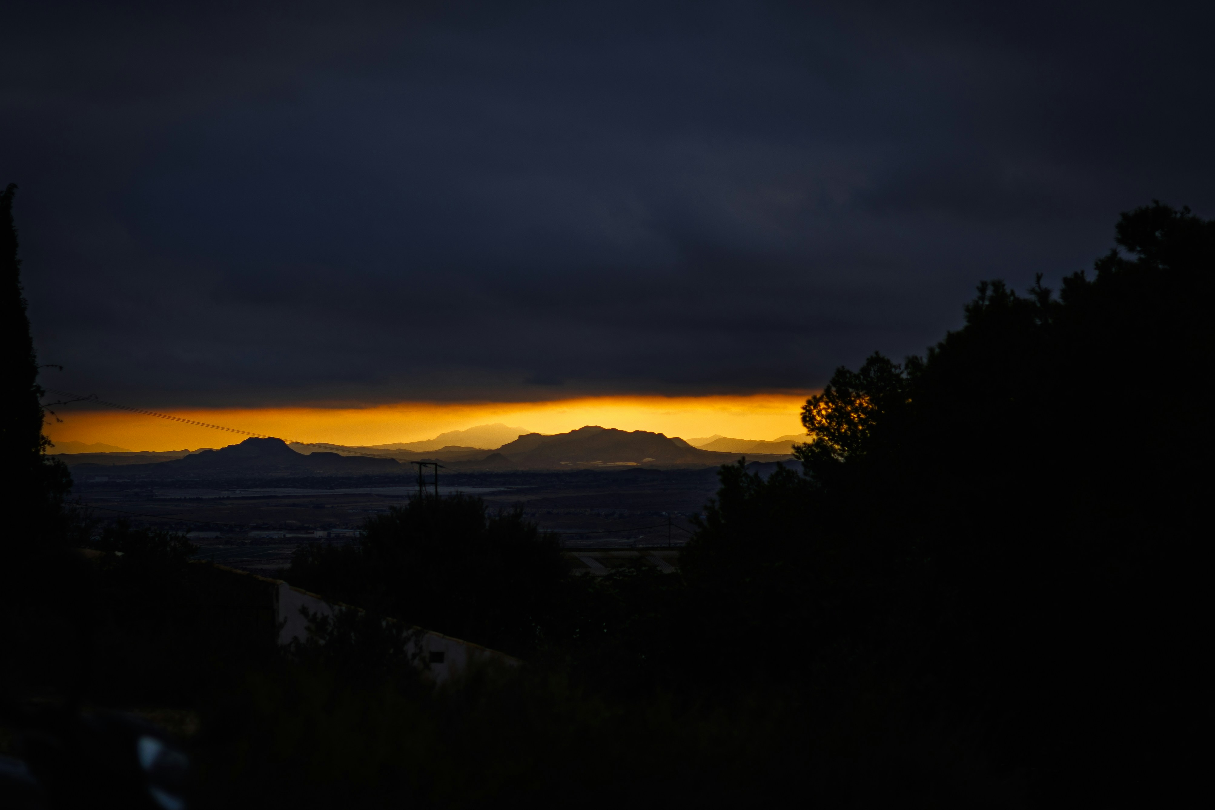 Montanhas distantes silhuetas contra um céu vibrante do pôr do sol.