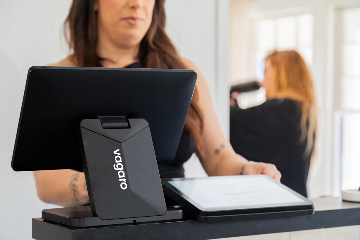 A small business owner reviewing a lengthy itemized invoice at a desk with a laptop nearby