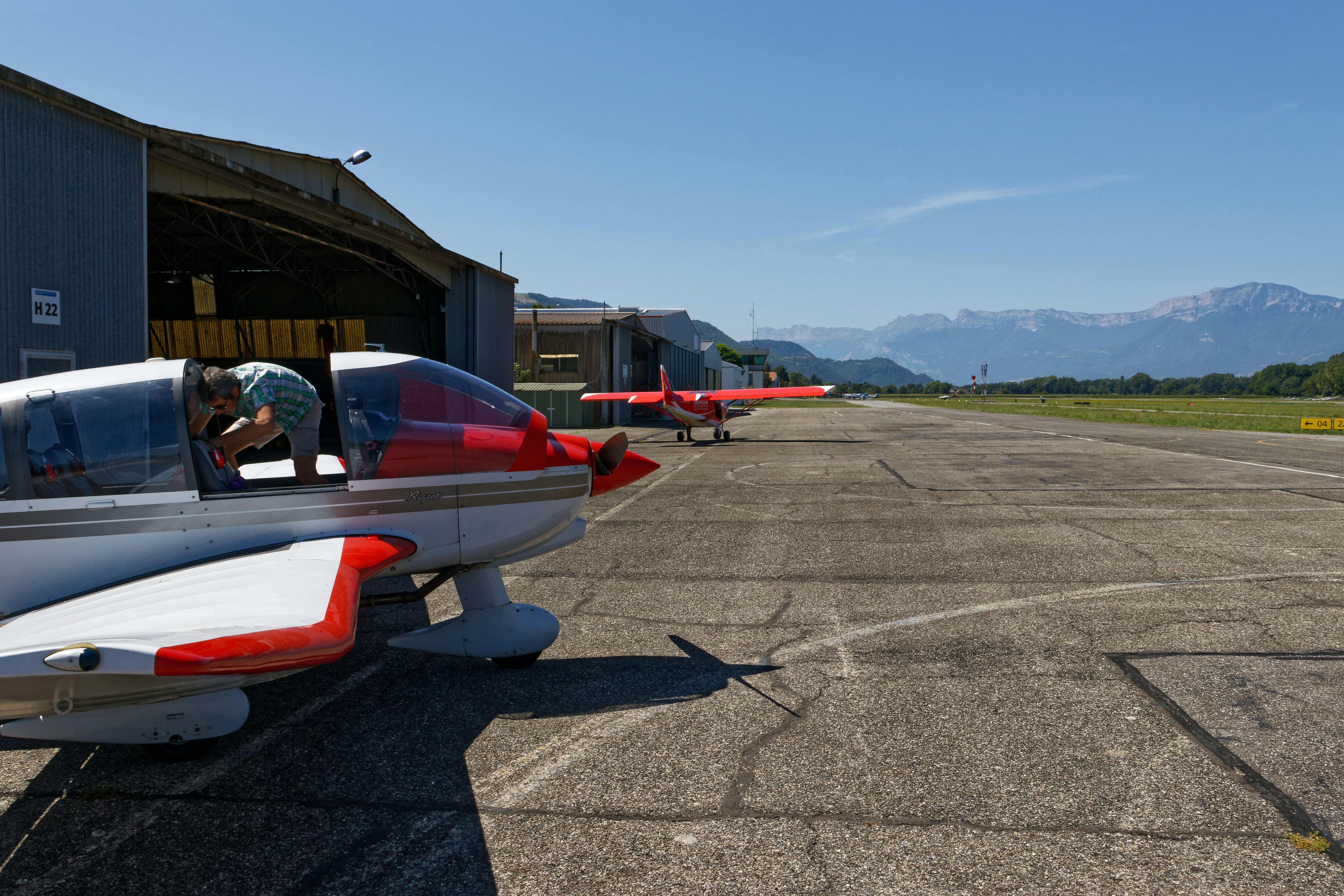 Small airplanes parked on a sunny airfield with mountains