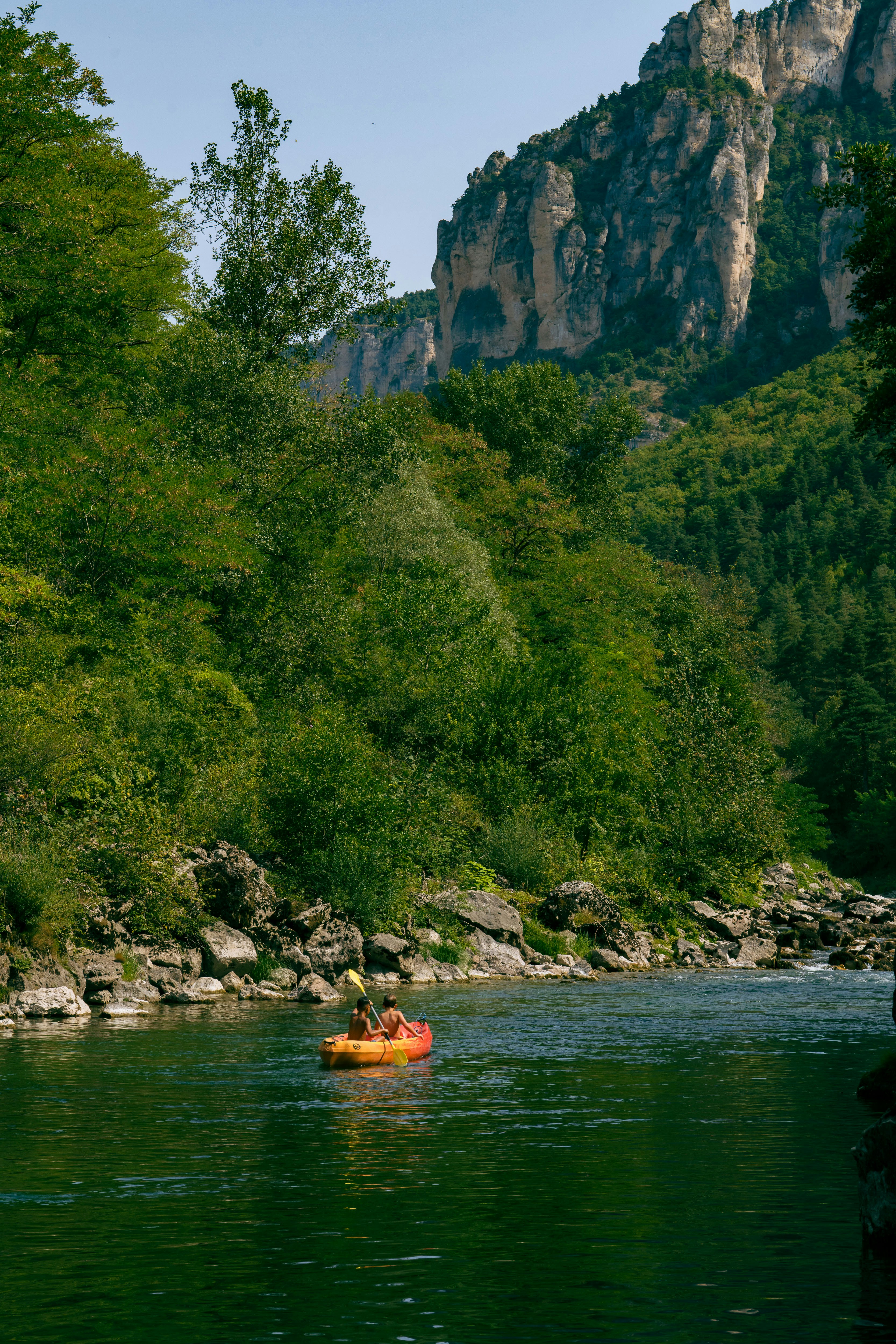 山のある川をカヤックで下る2人。