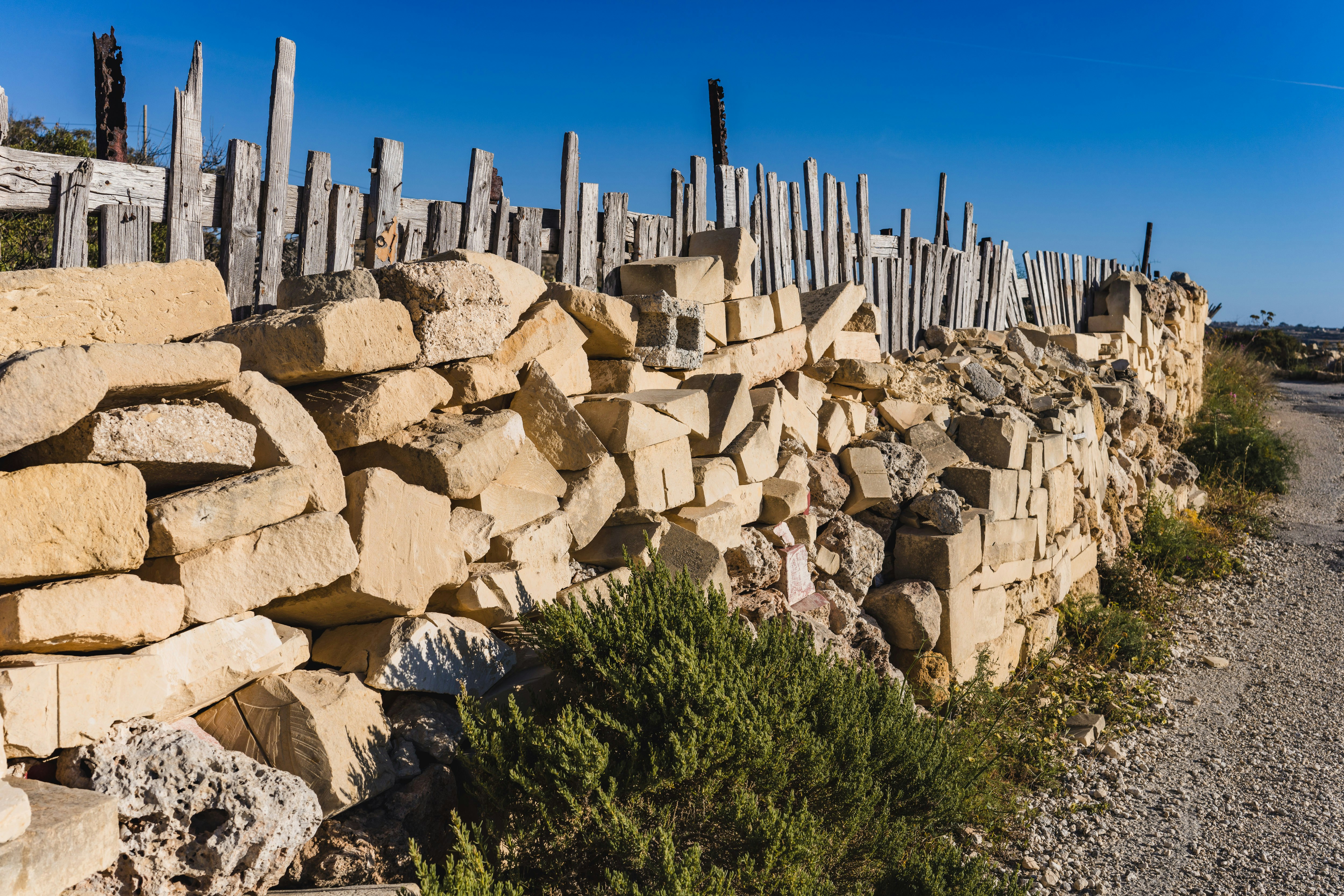 青空の下に木の柵のある石垣
