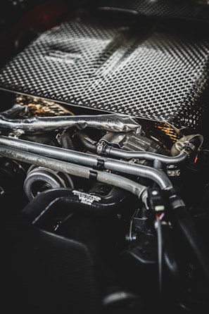 Close-up of a car engine with metal pipes and wires.