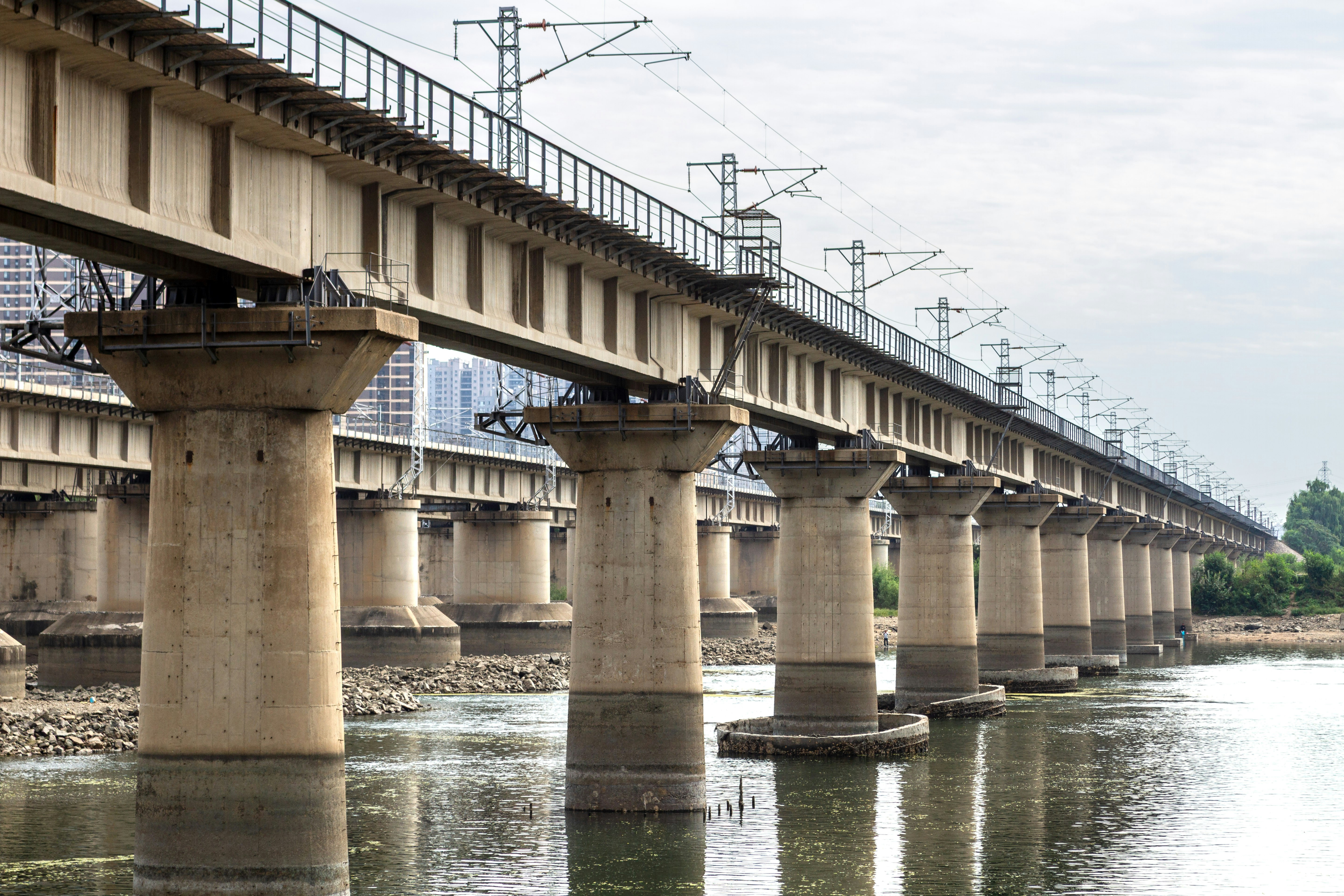 A long train bridge crosses over a calm river.