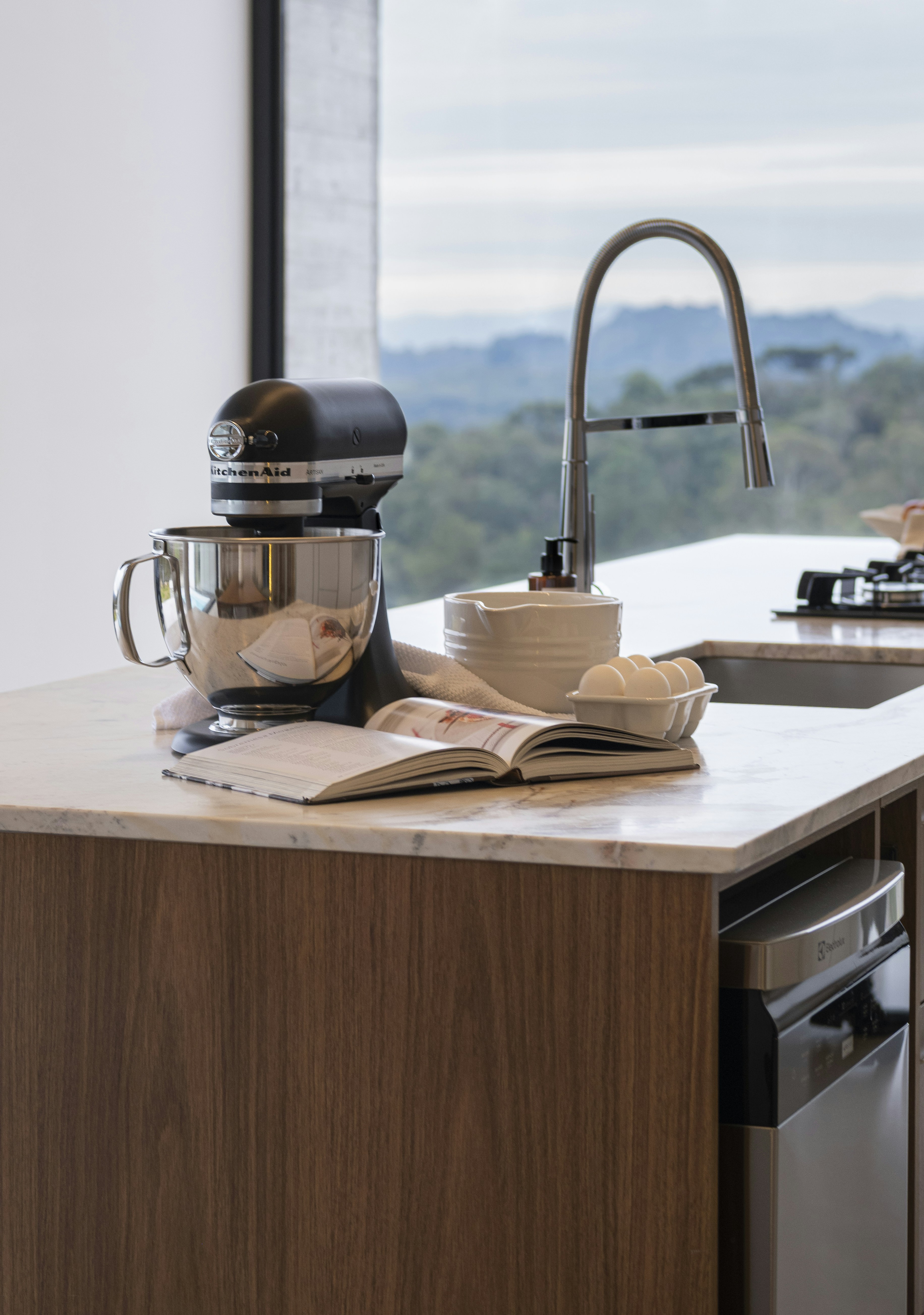 Stand mixer on kitchen island with open cookbook.