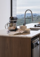 Stand mixer on kitchen island with open cookbook.