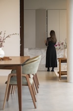 Woman in black dress opening modern kitchen cabinet