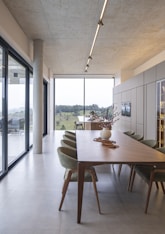 Modern dining room with large windows overlooking landscape.