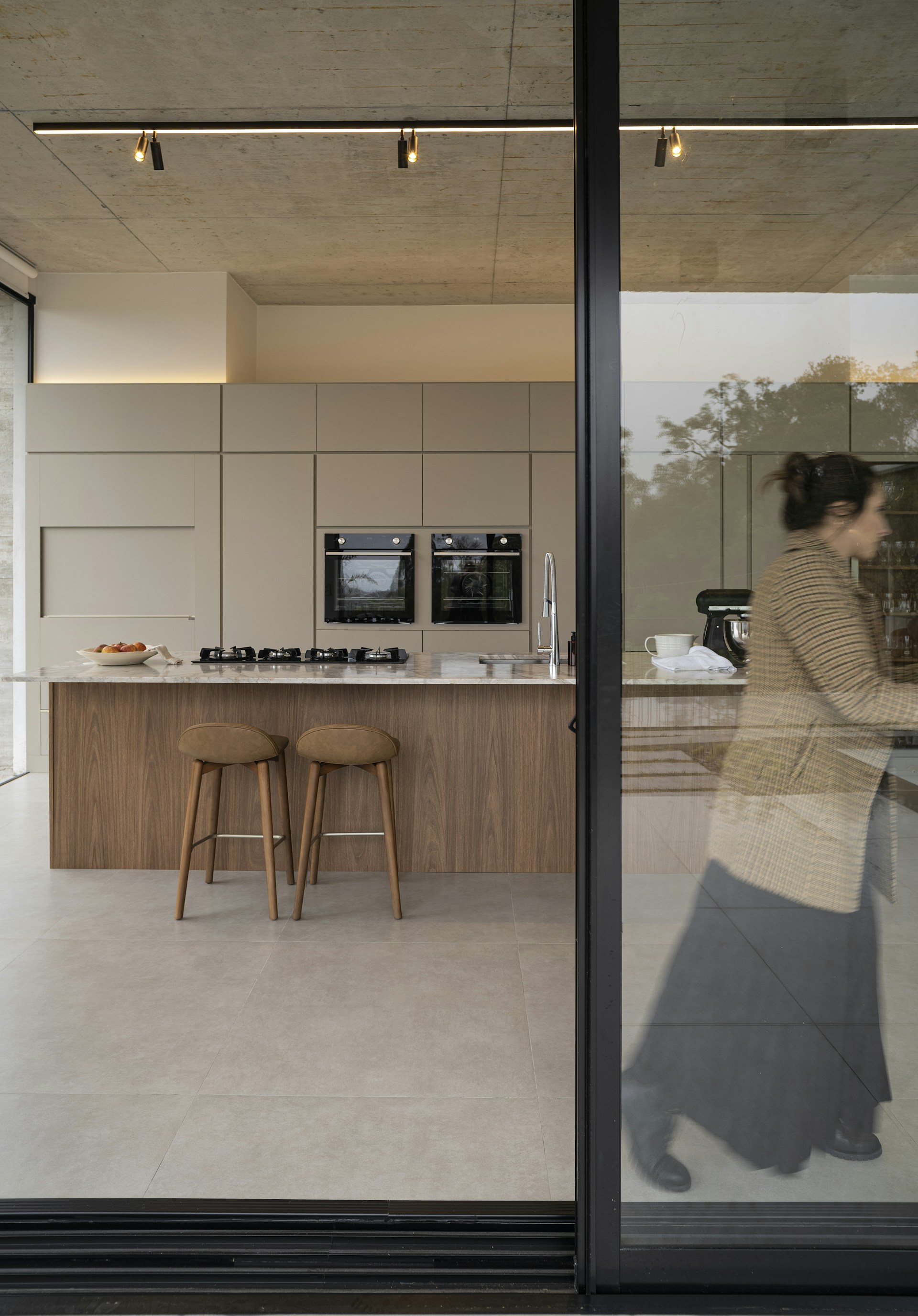 Woman walking past modern kitchen with island.