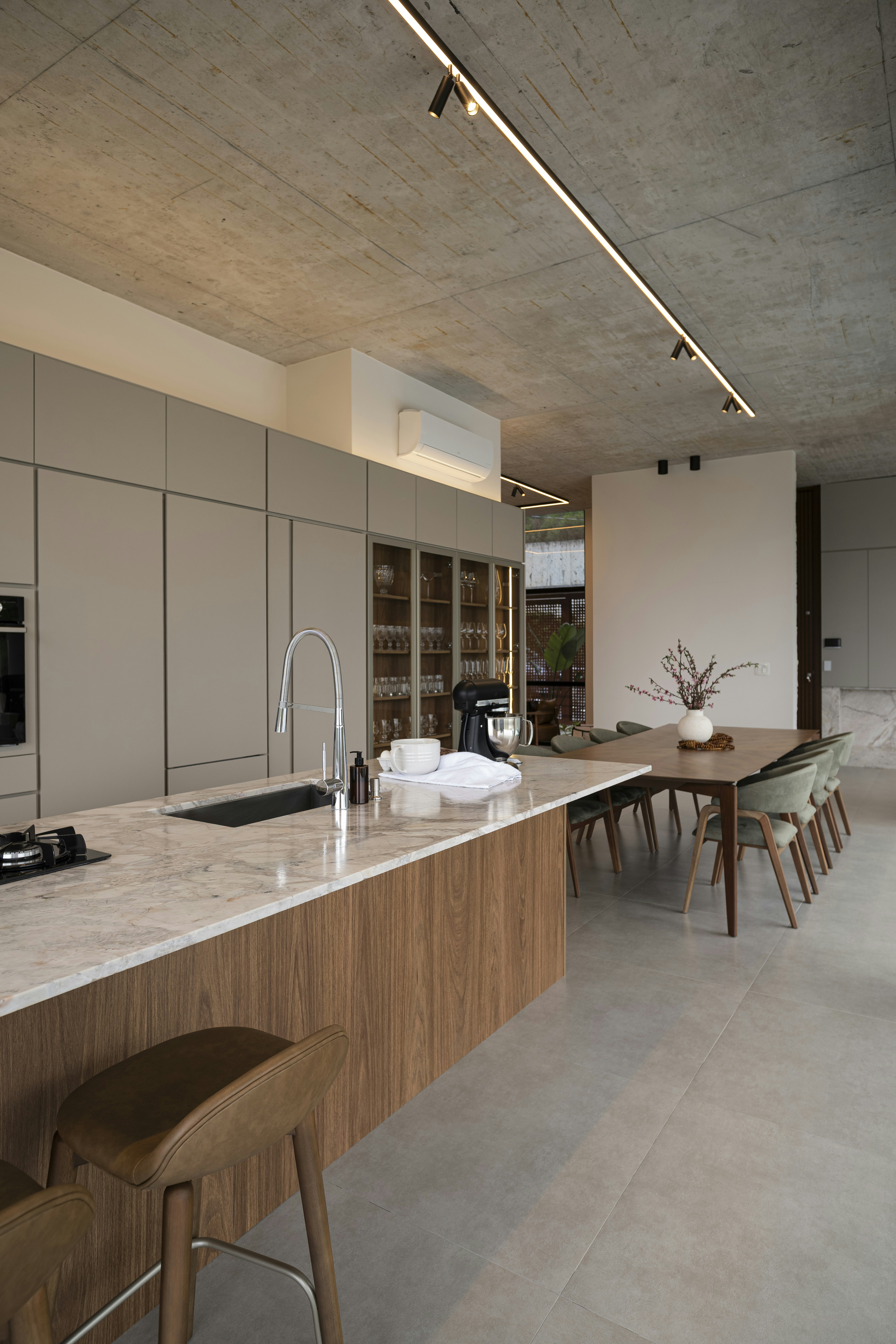 Modern kitchen island with dining area and concrete ceiling.