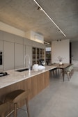 Modern kitchen island with dining area and concrete ceiling.