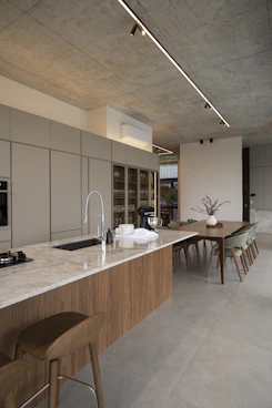 Modern kitchen island with dining area and concrete ceiling.