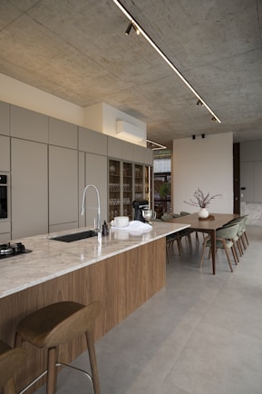Modern kitchen island with dining area and concrete ceiling.