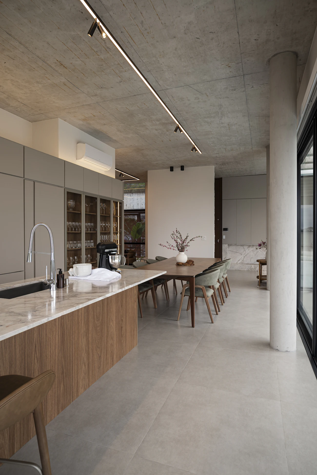 Cozinha integrada à sala de jantar, com armários de madeira e teto de concreto